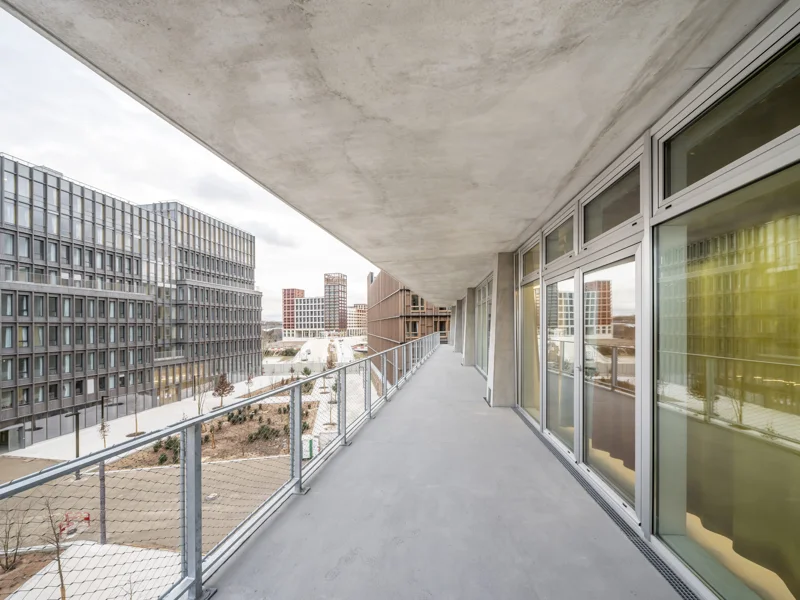 Długi balkon z oknami panoramicznymi i metalową balustradą